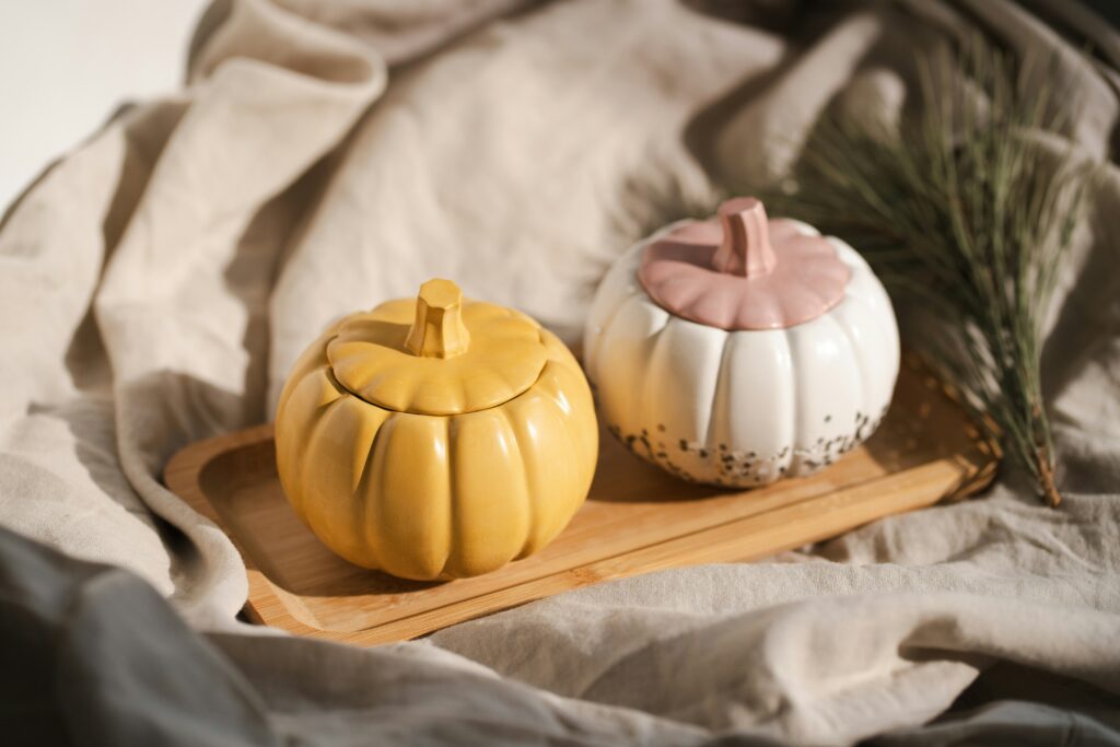 two light ceramic pumpkins on wood with a spring of rosemary