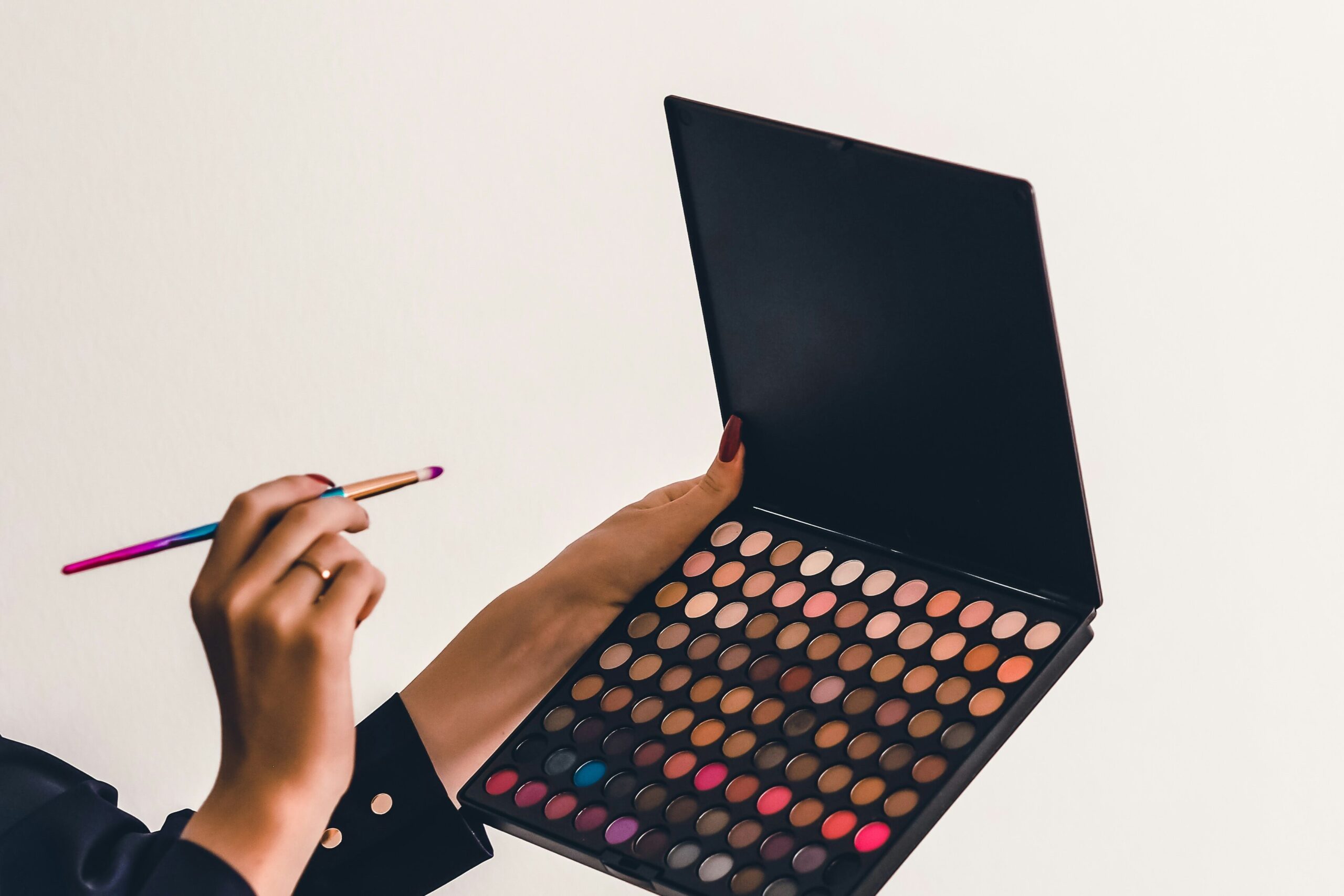 a person holding a brush about to use a makeup palette